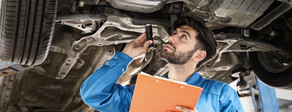 Mechanic inspecting underneath a vehicle as part of its MOT - MOT Testing Banbury